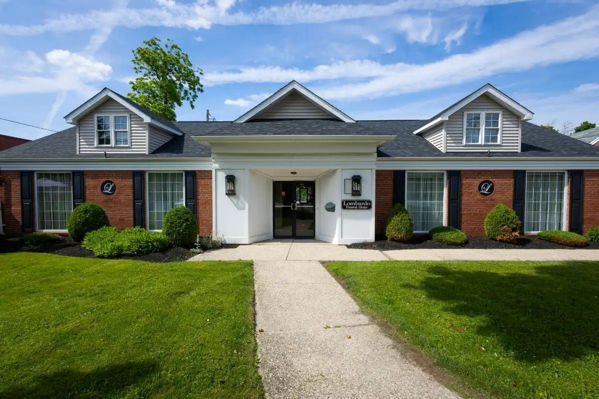 Brick building with green lawn, dormer windows, and a white entrance.