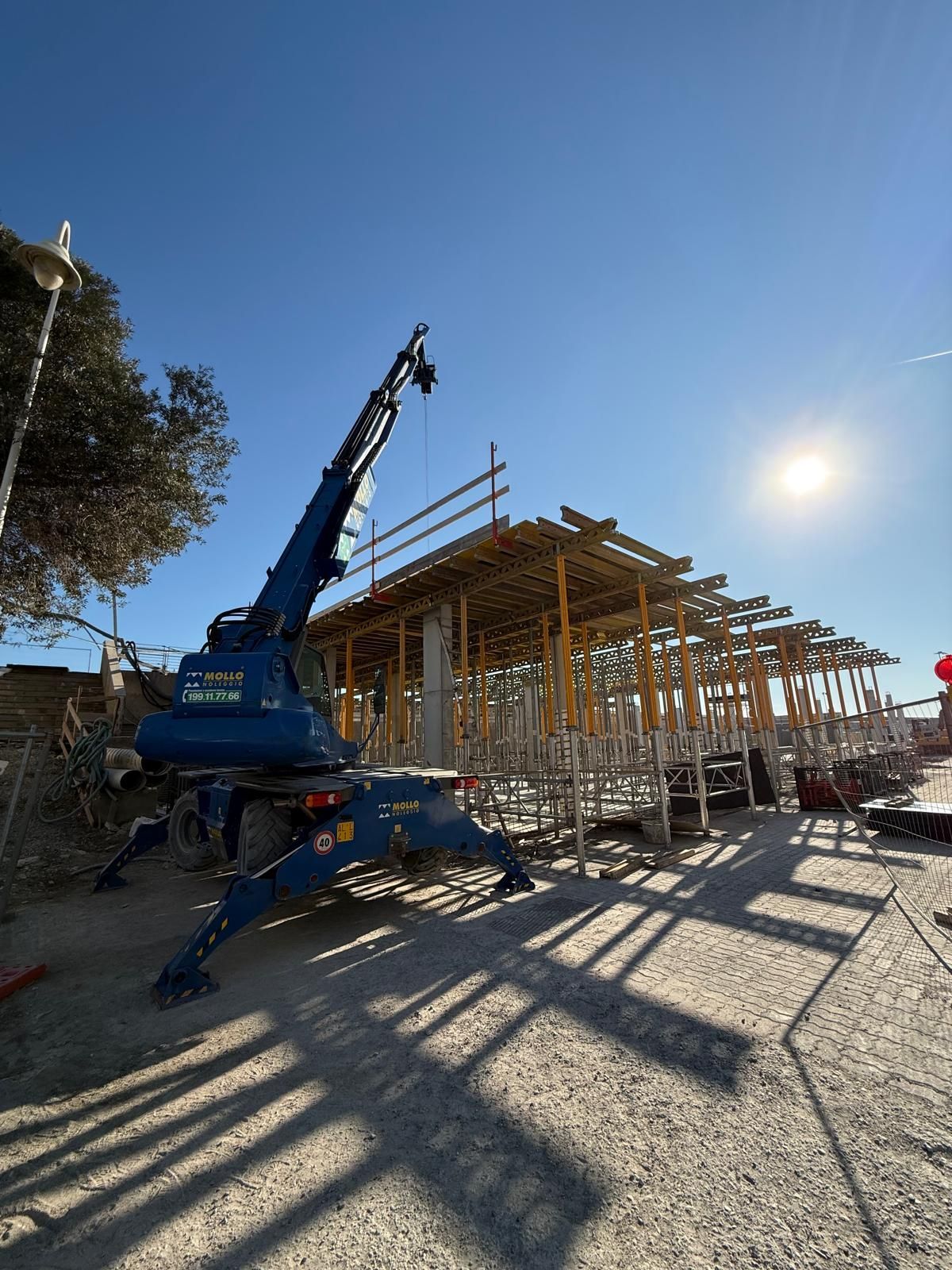 Una gru blu e un cantiere con impalcature sotto un sole splendente Geotecno Genova