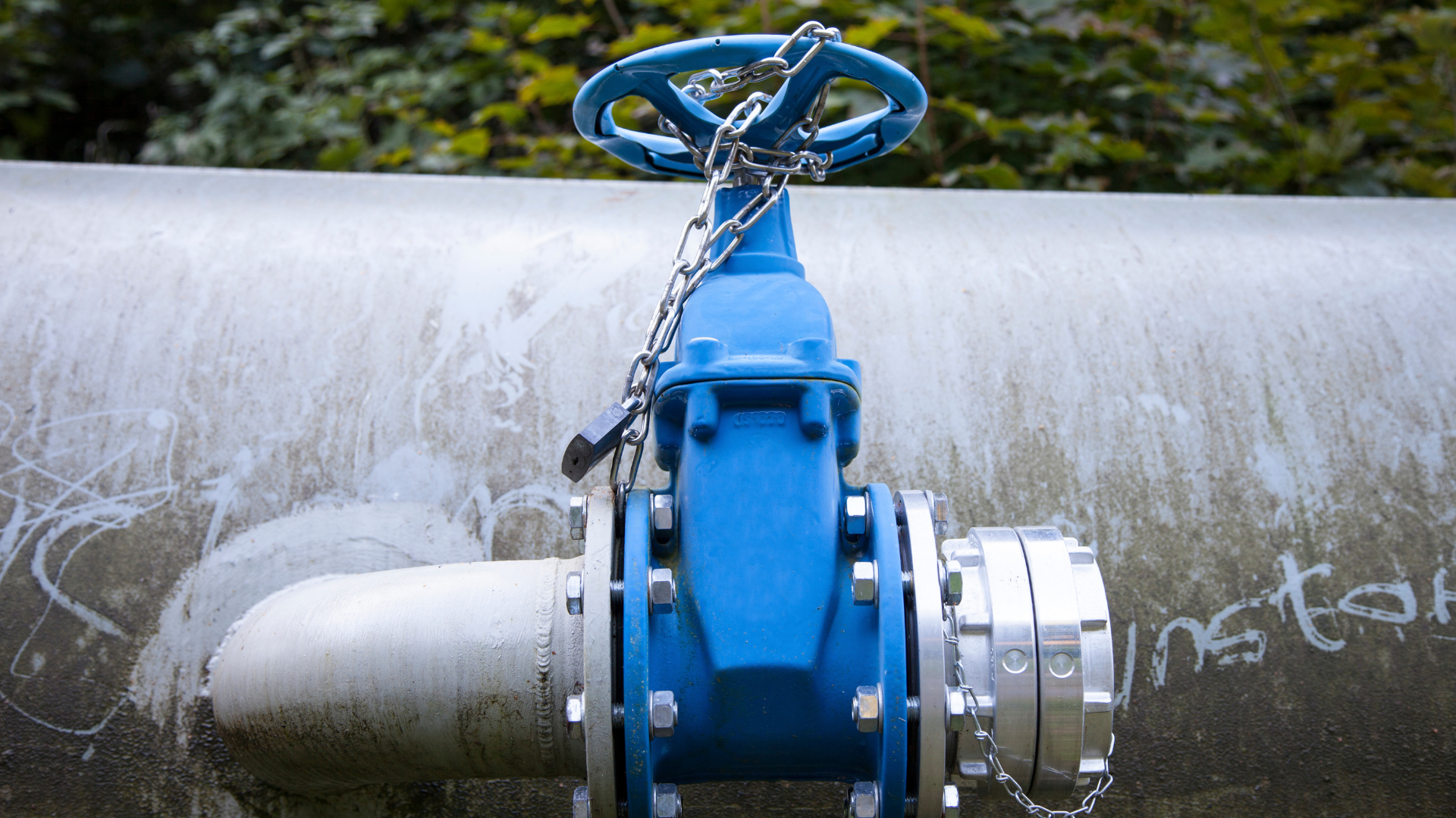 A blue valve is attached to a pipe with chains.