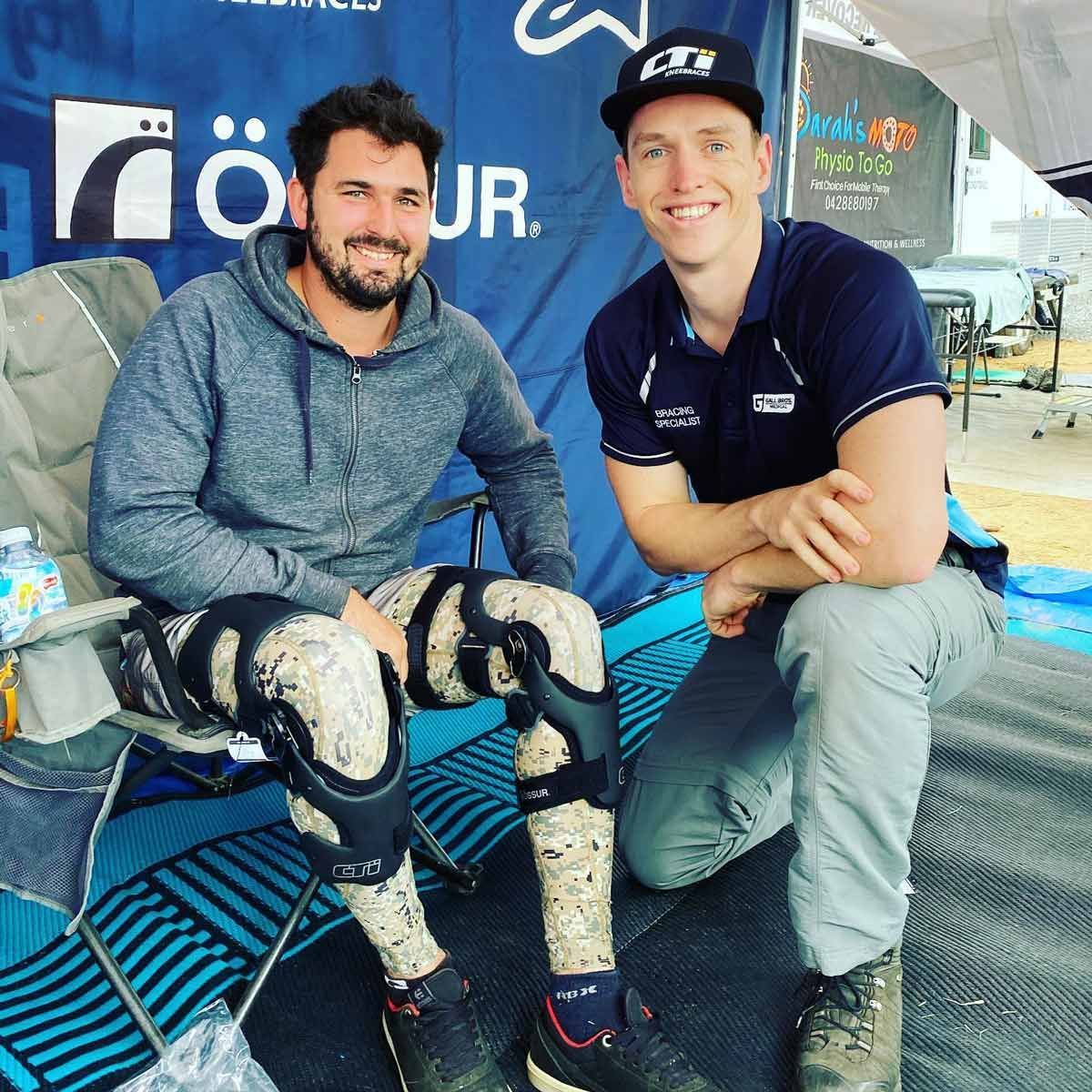 A Man With a Knee Brace is Kneeling Next to Another Man — Gall Bros Medical in Robina, QLD