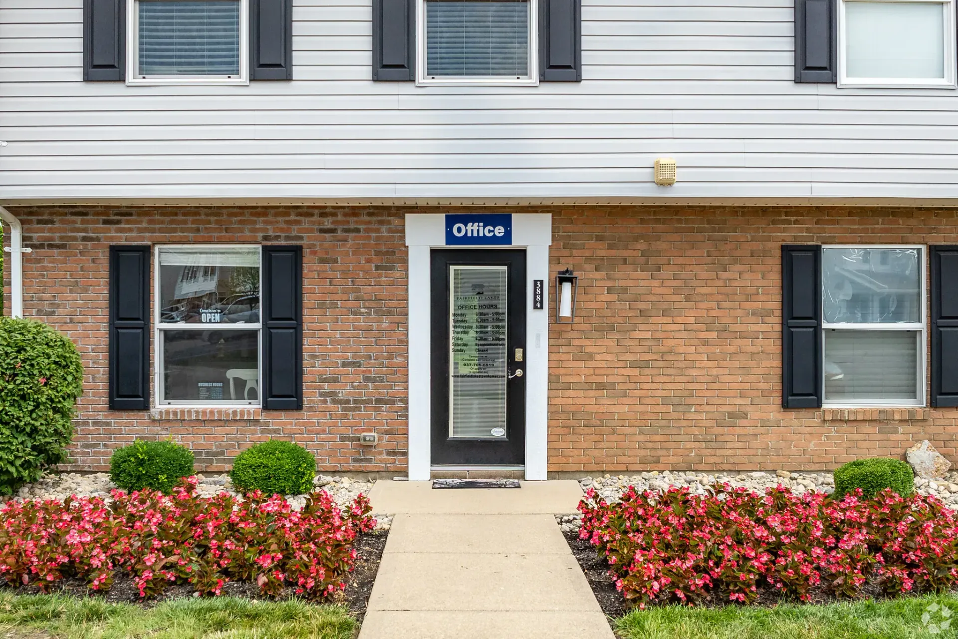 Apartment building exterior with brick and siding, a pathway, and landscaping.