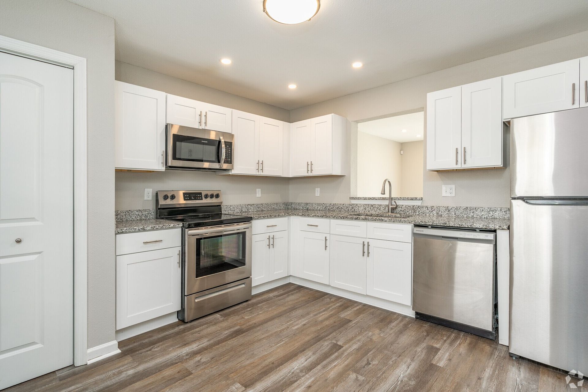 White kitchen with stainless steel appliances and granite countertops.
