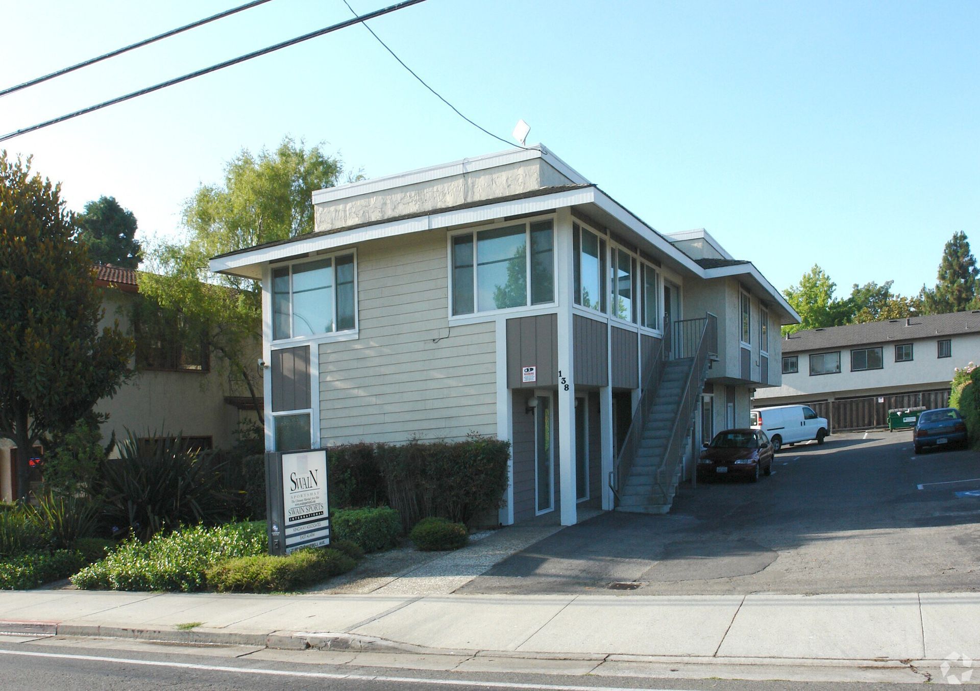 Man in gray suit and blue shirt smiles, headshot against a gray backdrop.