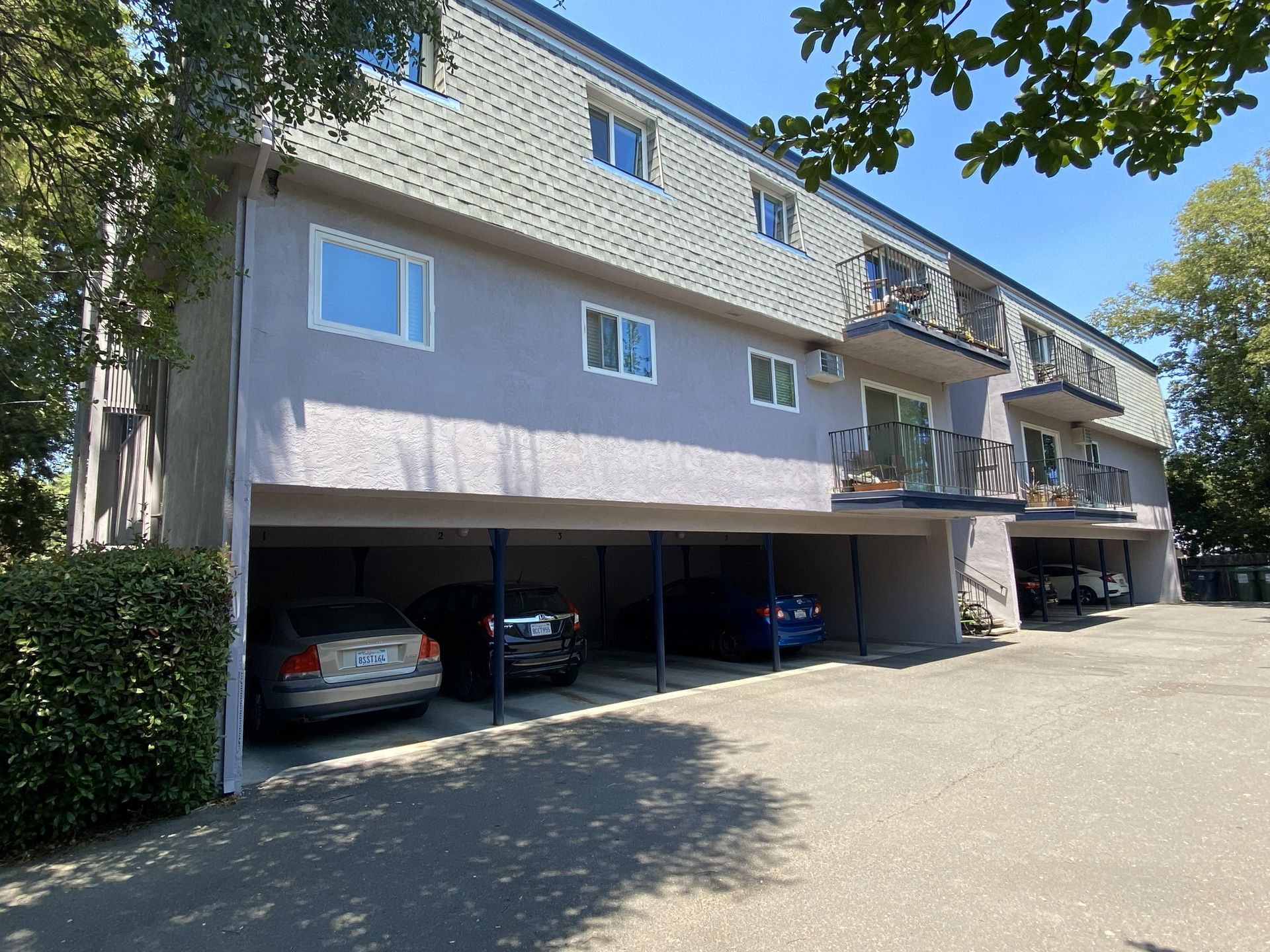 Two-story building with a wooden fence and outdoor seating area on a sunny day.