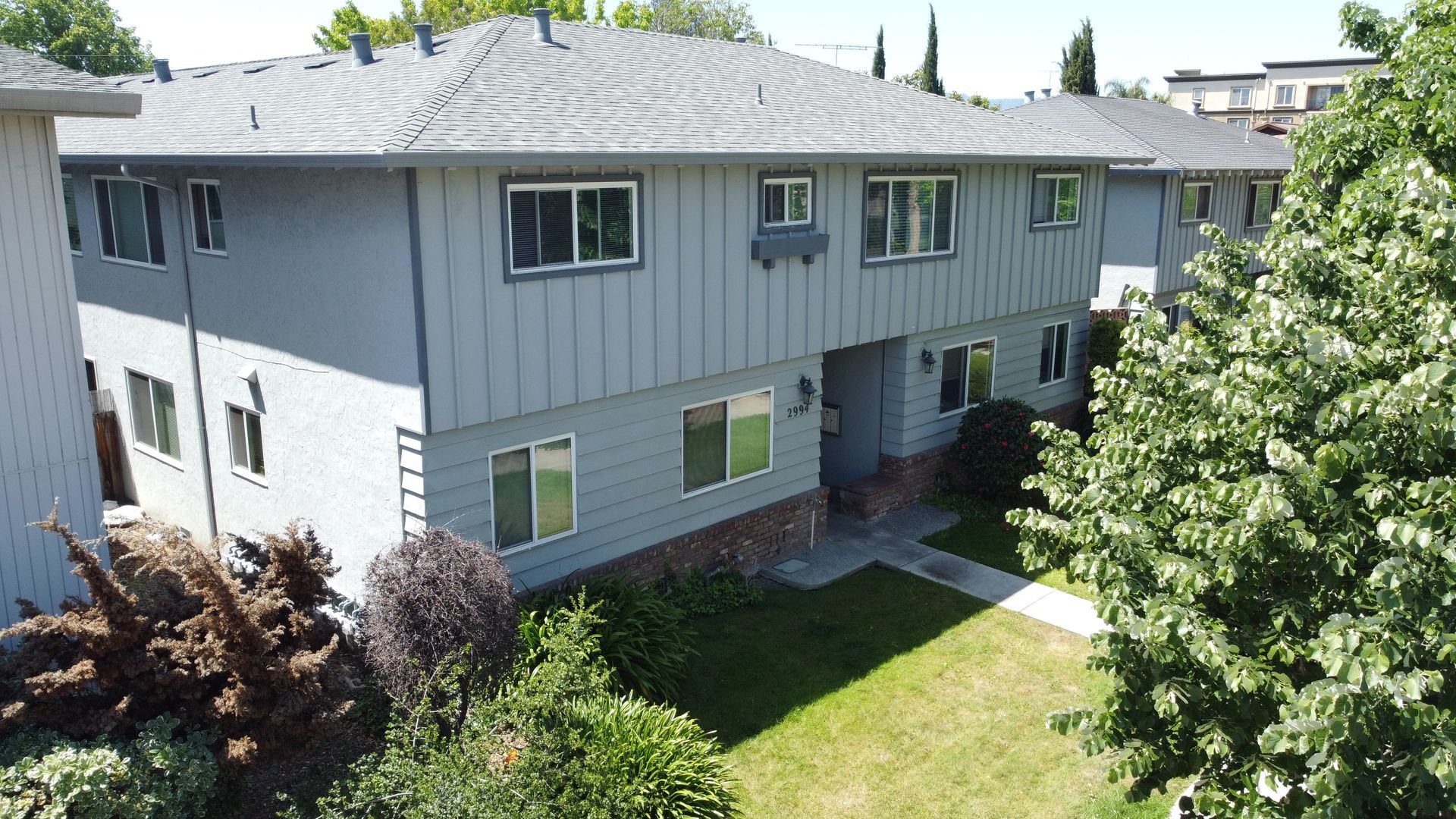 Two-story apartment building with light blue siding, gray roof, and green lawn.