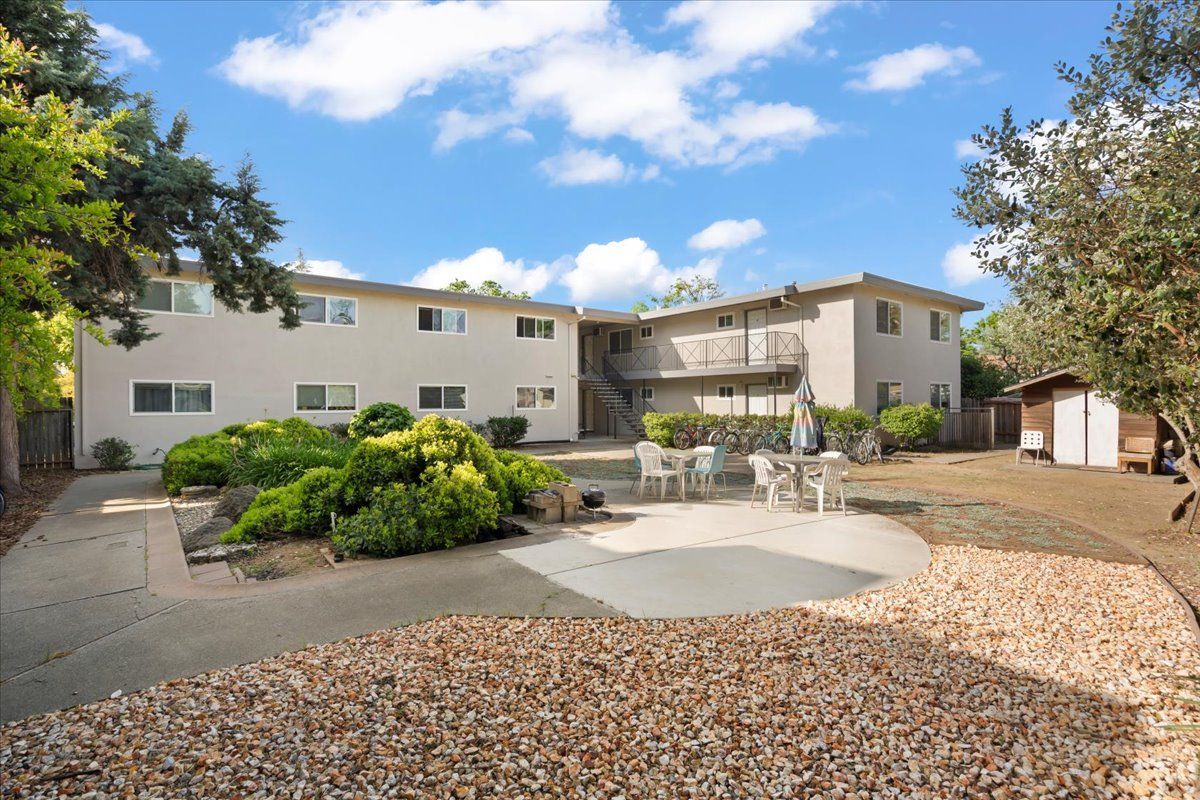Man in gray suit and blue shirt smiles, headshot against a gray backdrop.