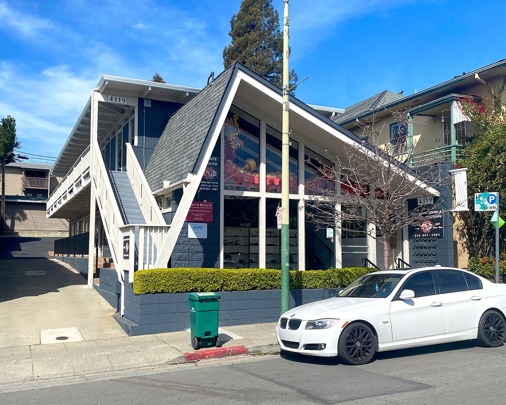 Modern building with a V-shaped roof, large windows, and a white car parked in front.