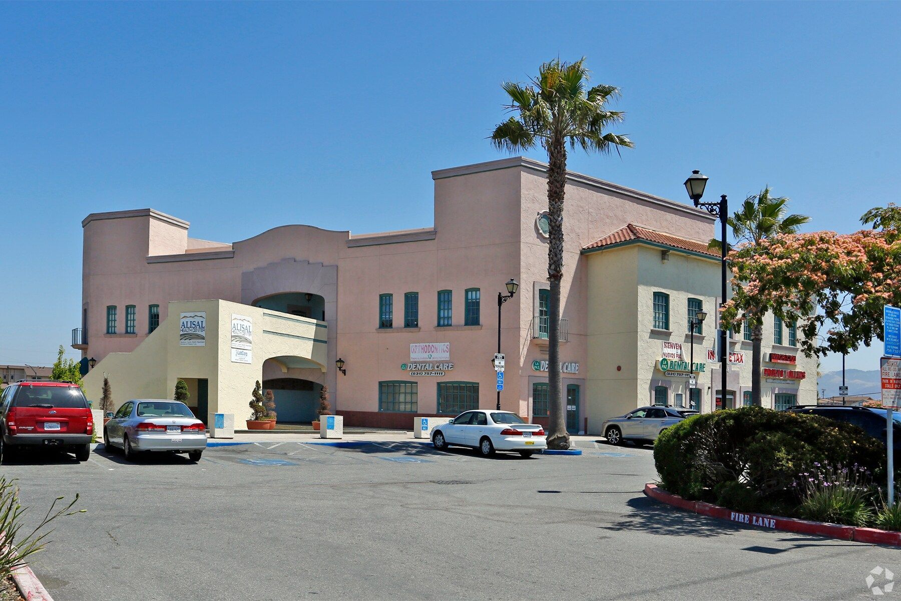 Row of modern townhouses with grey, yellow, and white siding, black windows, and a black fence.