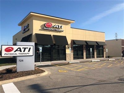 Exterior of ATI Physical Therapy clinic, light beige building with black awnings, sign on front.