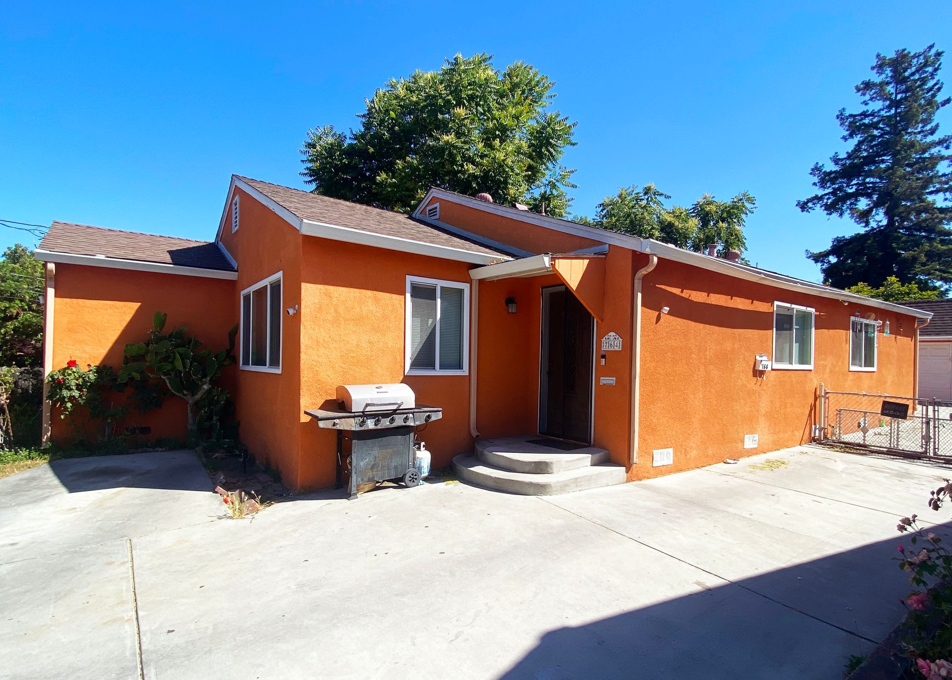 Multi-story apartment building with white, gray, and brown facade against a blue sky.