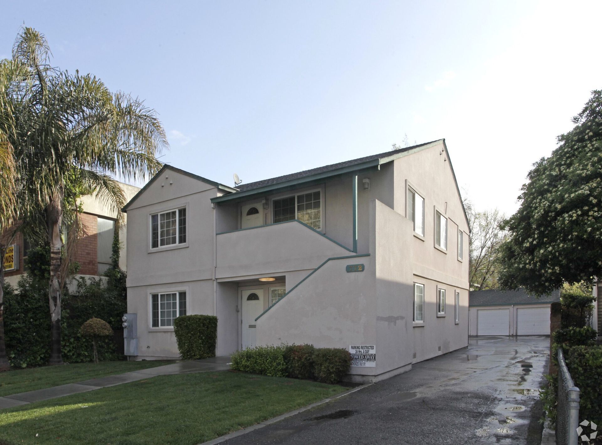 Two-story beige apartment building with dark trim and a short driveway.