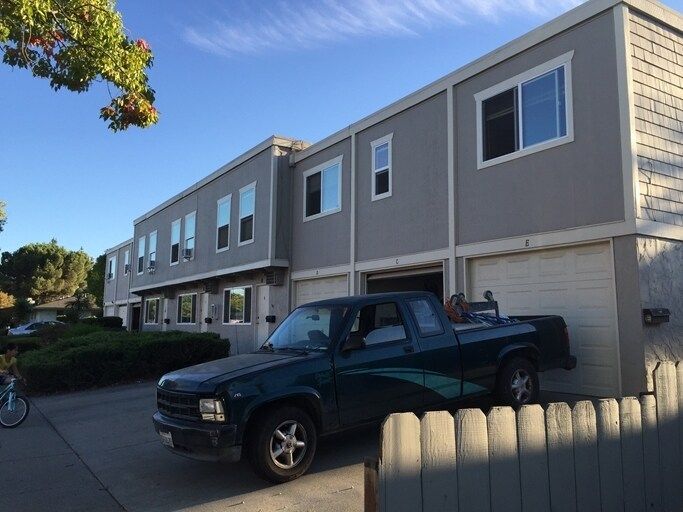 Man in gray suit and blue shirt smiles, headshot against a gray backdrop.
