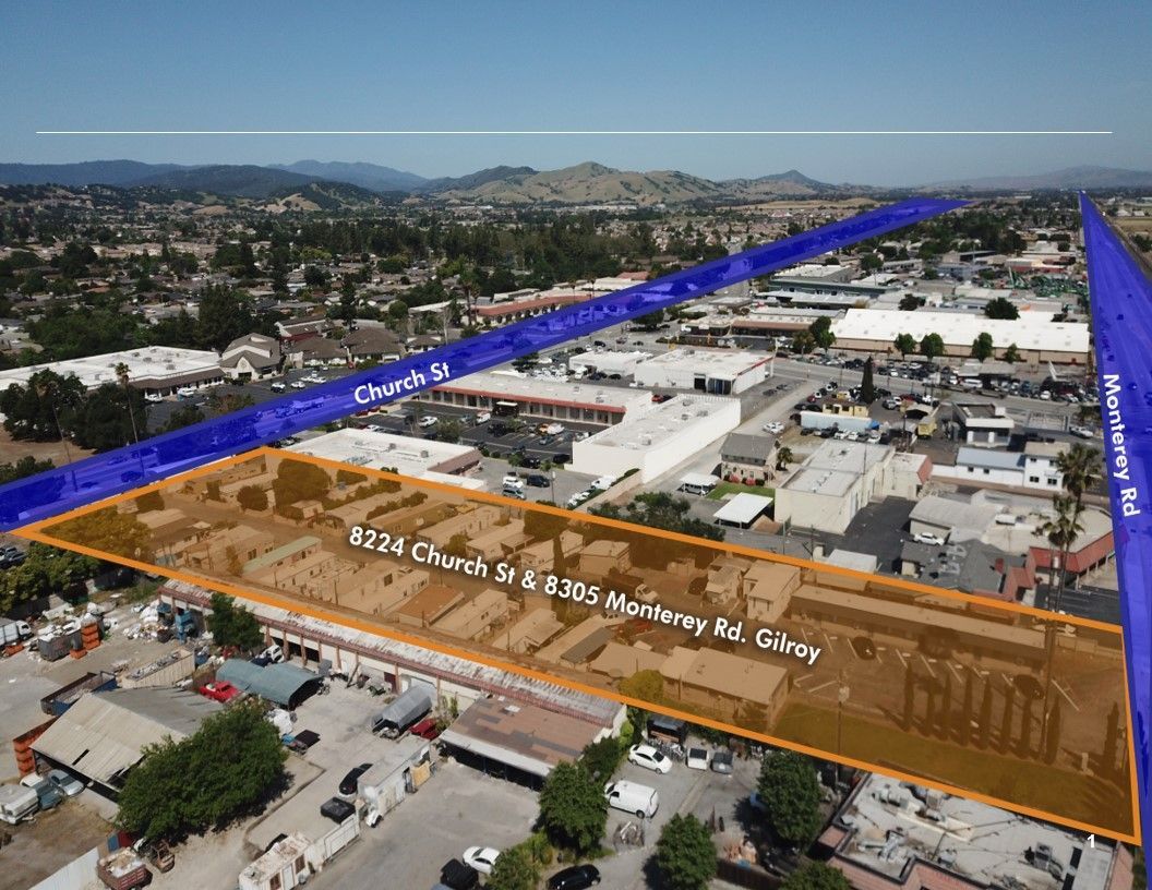 Parking lot with arrows, a utility pole, and small, one-story buildings.