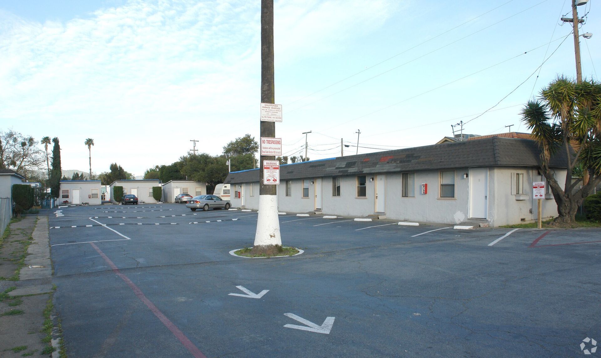 Parking lot with arrows, a utility pole, and small, one-story buildings.