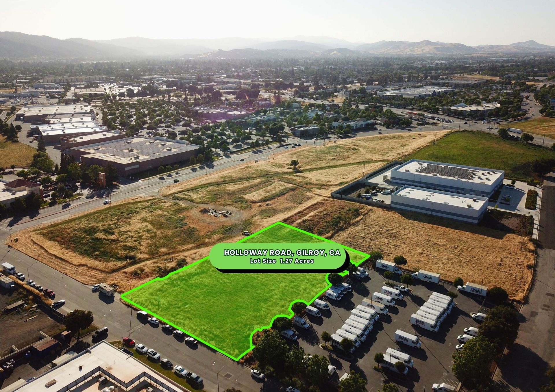 Aerial view of undeveloped land with a highlighted section, surrounded by buildings and a parking lot.