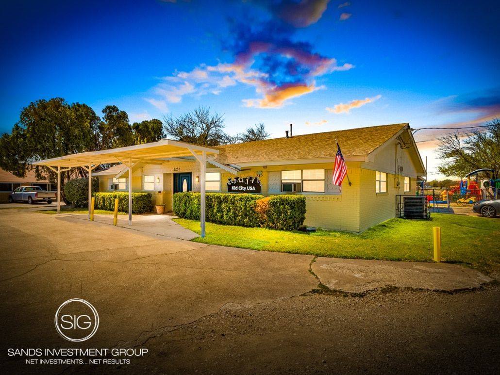 Yellow building with awning, American flag, sign, and cars on a sunny day.