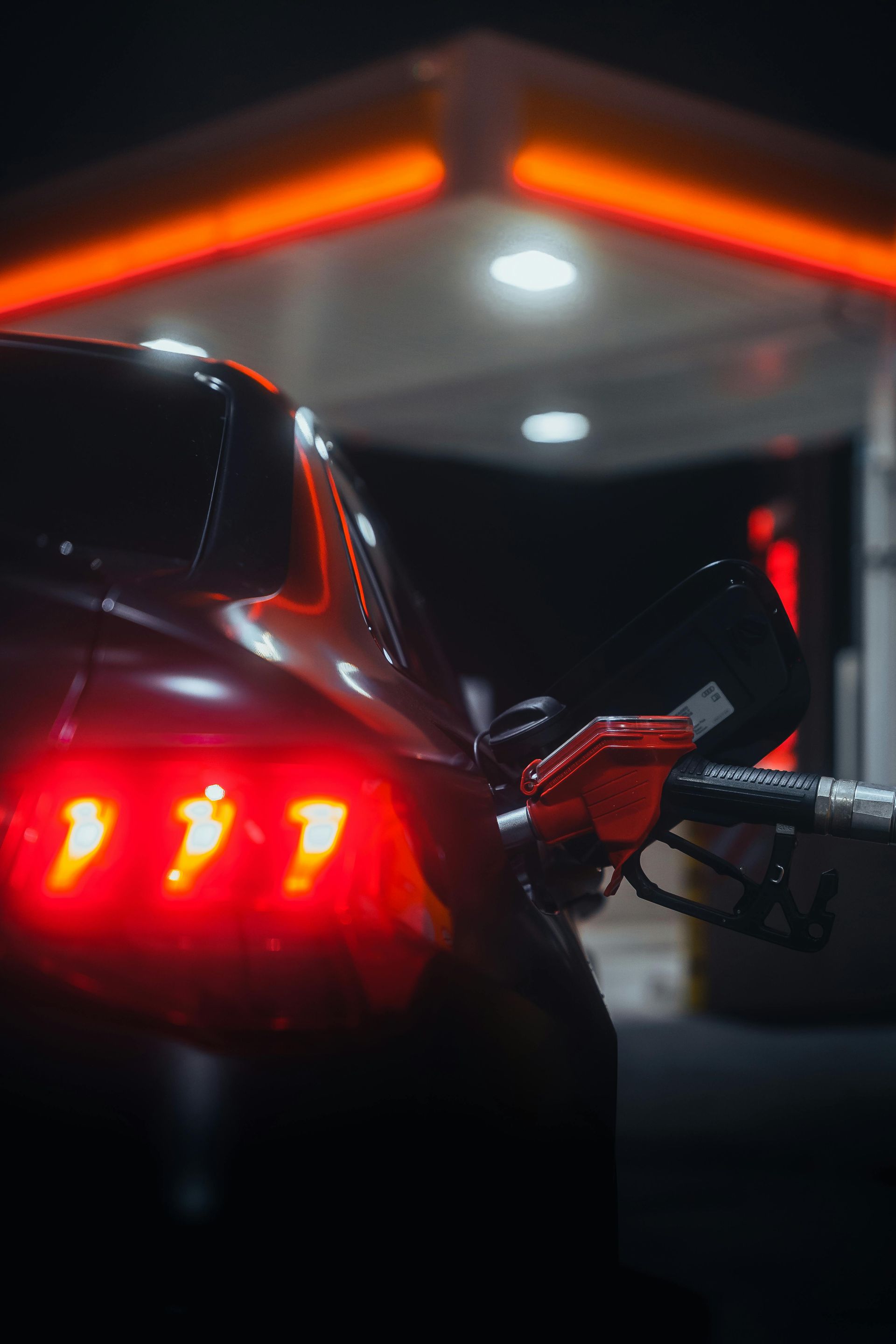 Gas station at night; Shell logo visible. Lit canopy over fuel pumps, convenience store in background.