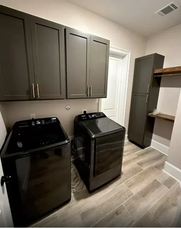 A laundry room with a washer and dryer and cabinets.
