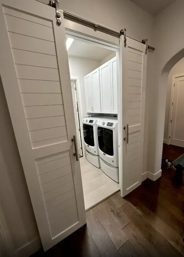 A laundry room with a washer and dryer and sliding barn doors.