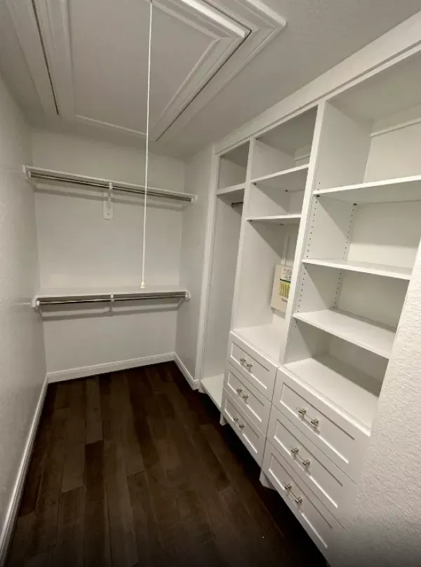 A walk in closet with lots of shelves and drawers.