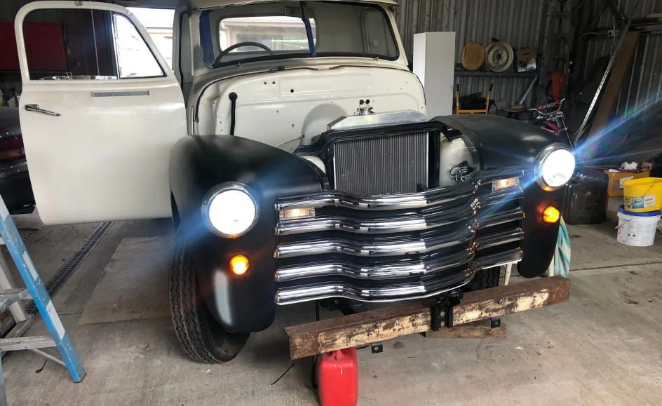 An Old Truck Is Sitting In A Garage With Its Doors Open — REM Auto Electrics In Lake Macquarie, NSW