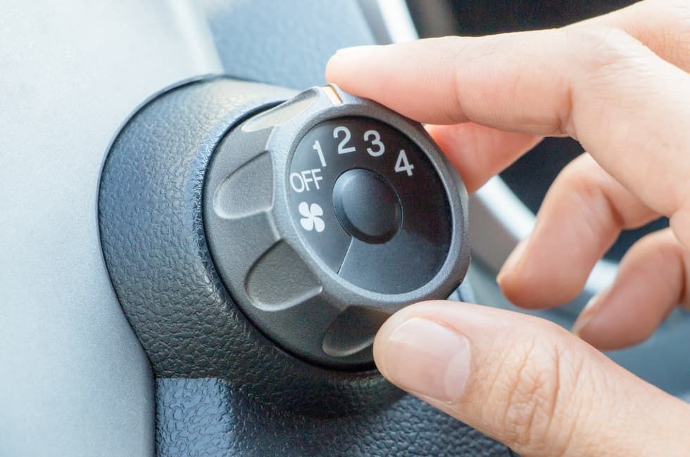 A Person Is Adjusting The Air Conditioner In A Car — REM Auto Electrics In Cardiff, NSW