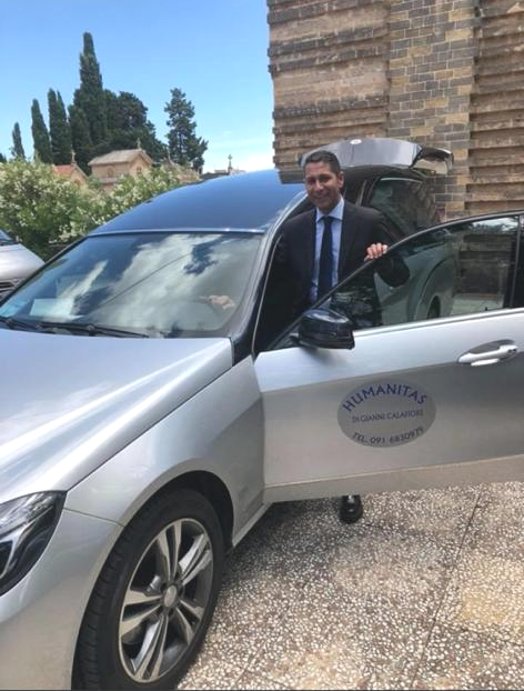 Auto per servizio funebre con addetto dell'azienda in giacca e cravatta.