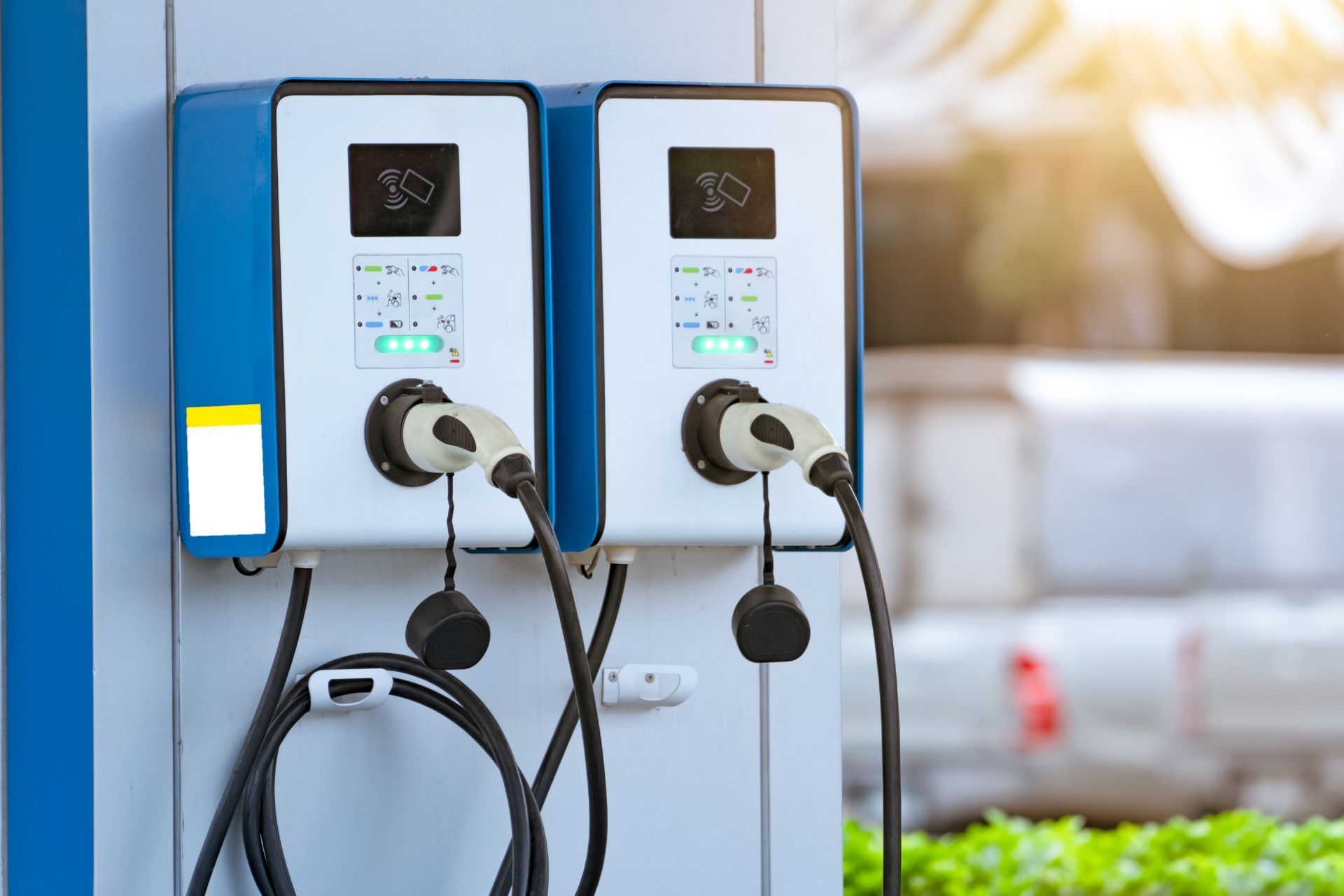 two electric cars are being charged at a charging station .