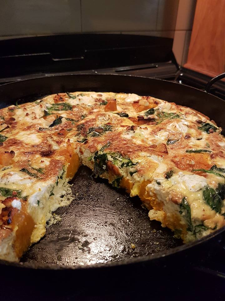 A pizza is cooking in a pan on a stove