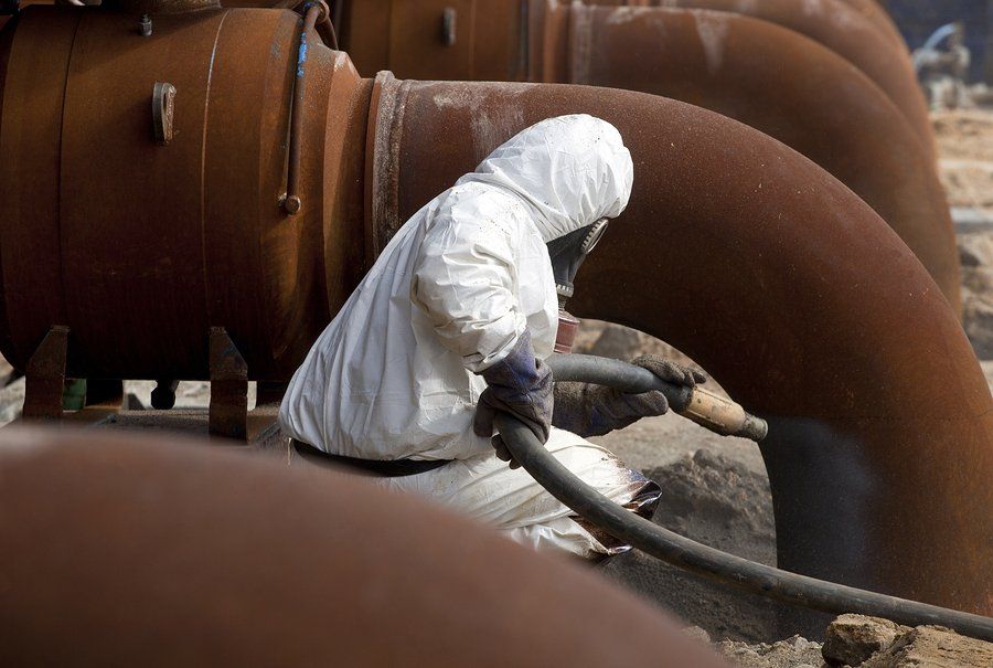 worker in white cleaning the metal pipe