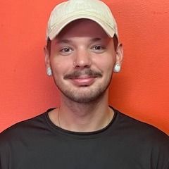 A man wearing a hat and a black shirt is smiling for the camera.