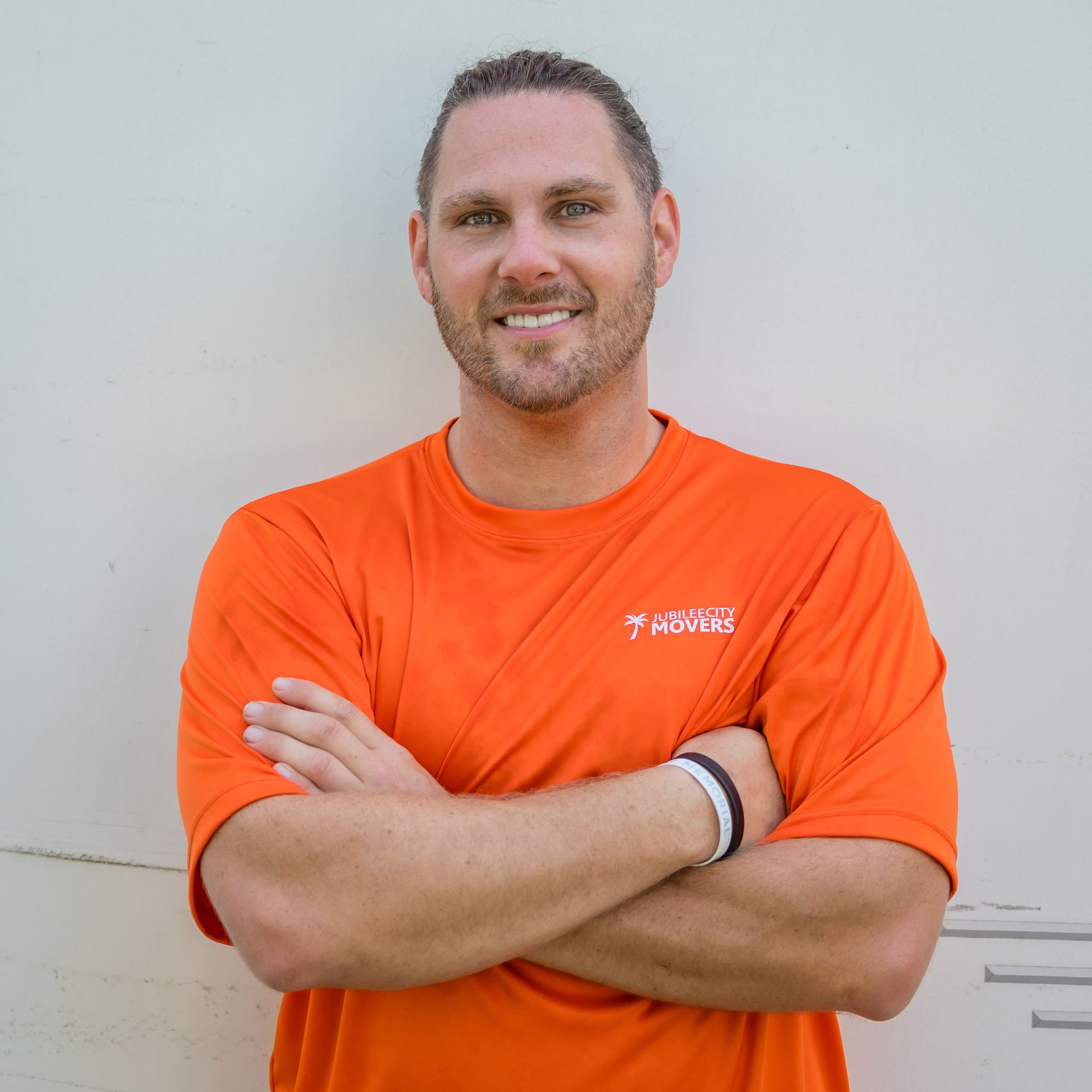 A man in an orange shirt has his arms crossed