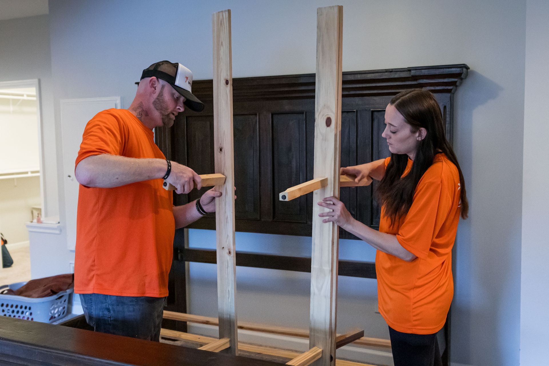 A man and a woman are working on a piece of wood.