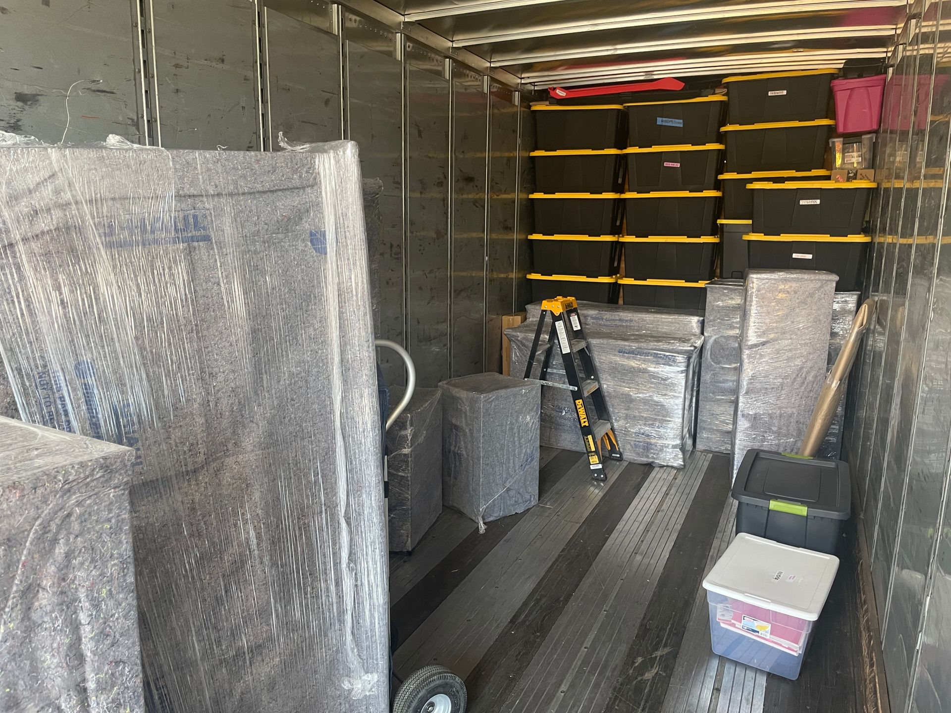 The inside of a moving truck filled with boxes and a ladder.