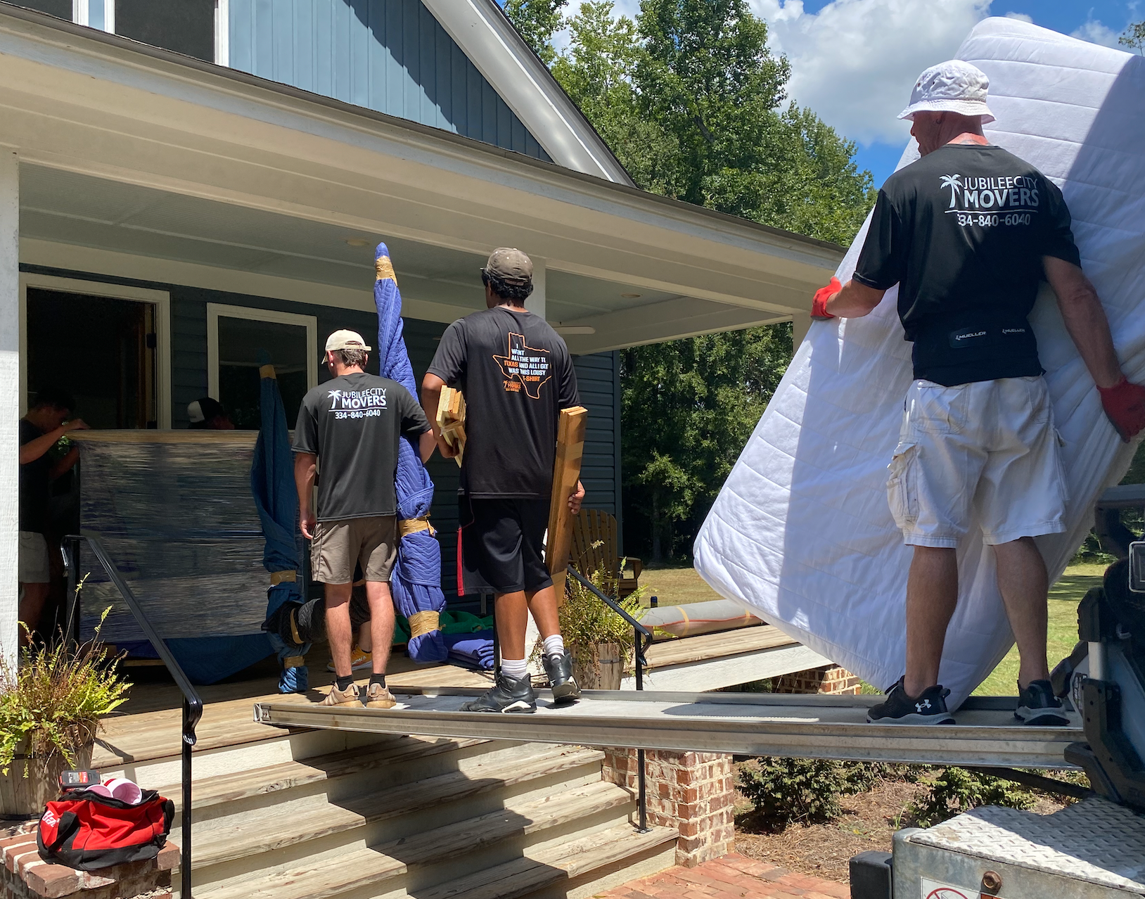 A group of men are carrying a large white mattress into a house.