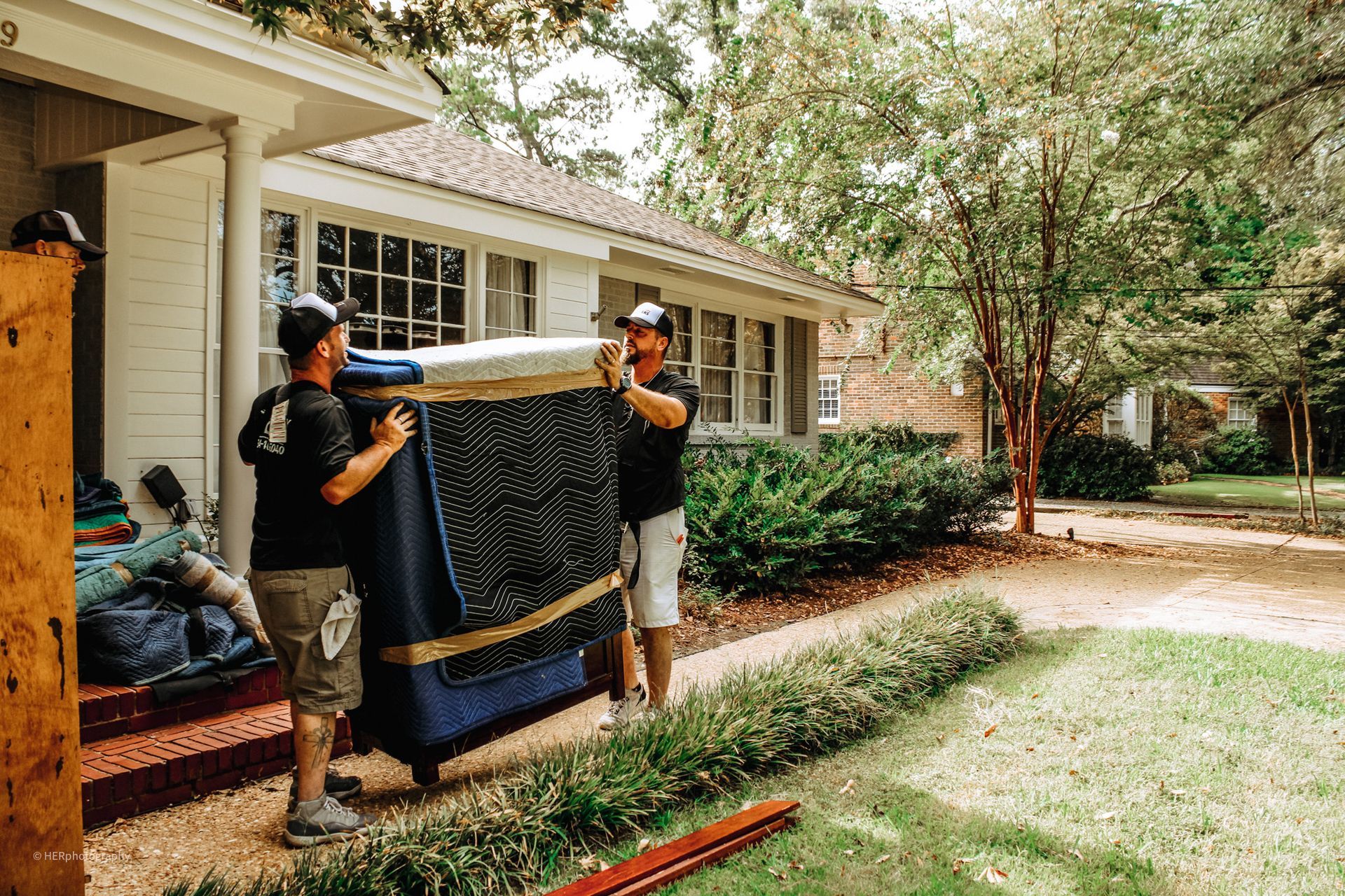 Two men are carrying a piano into a house.