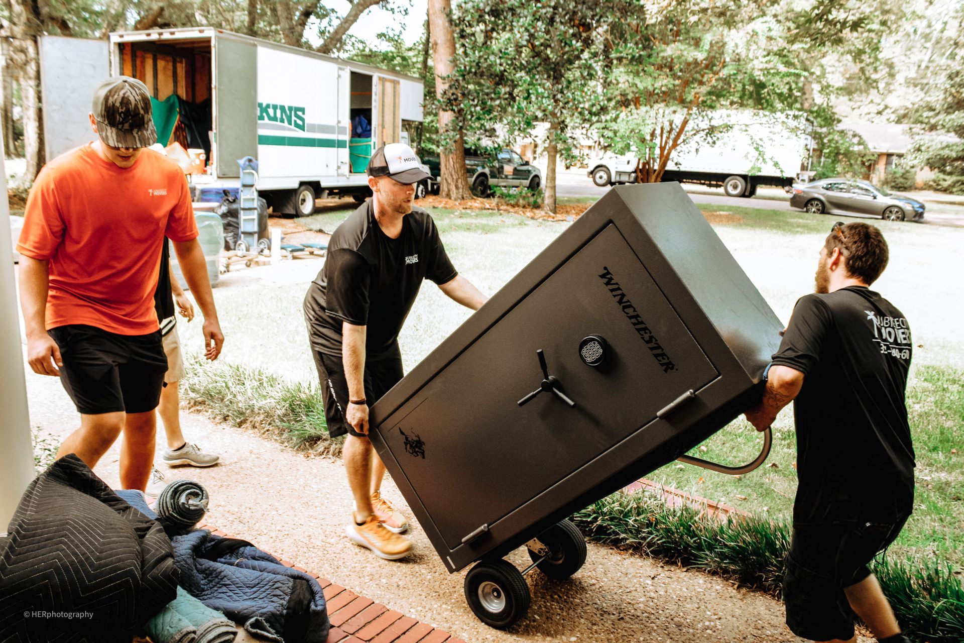 A group of men are carrying a large safe on a cart.