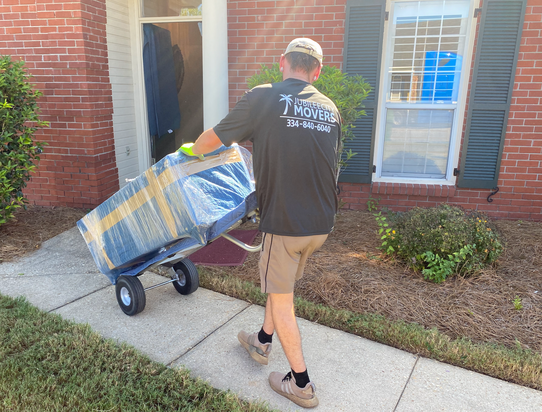 A man is pushing a cart full of boxes down a sidewalk.