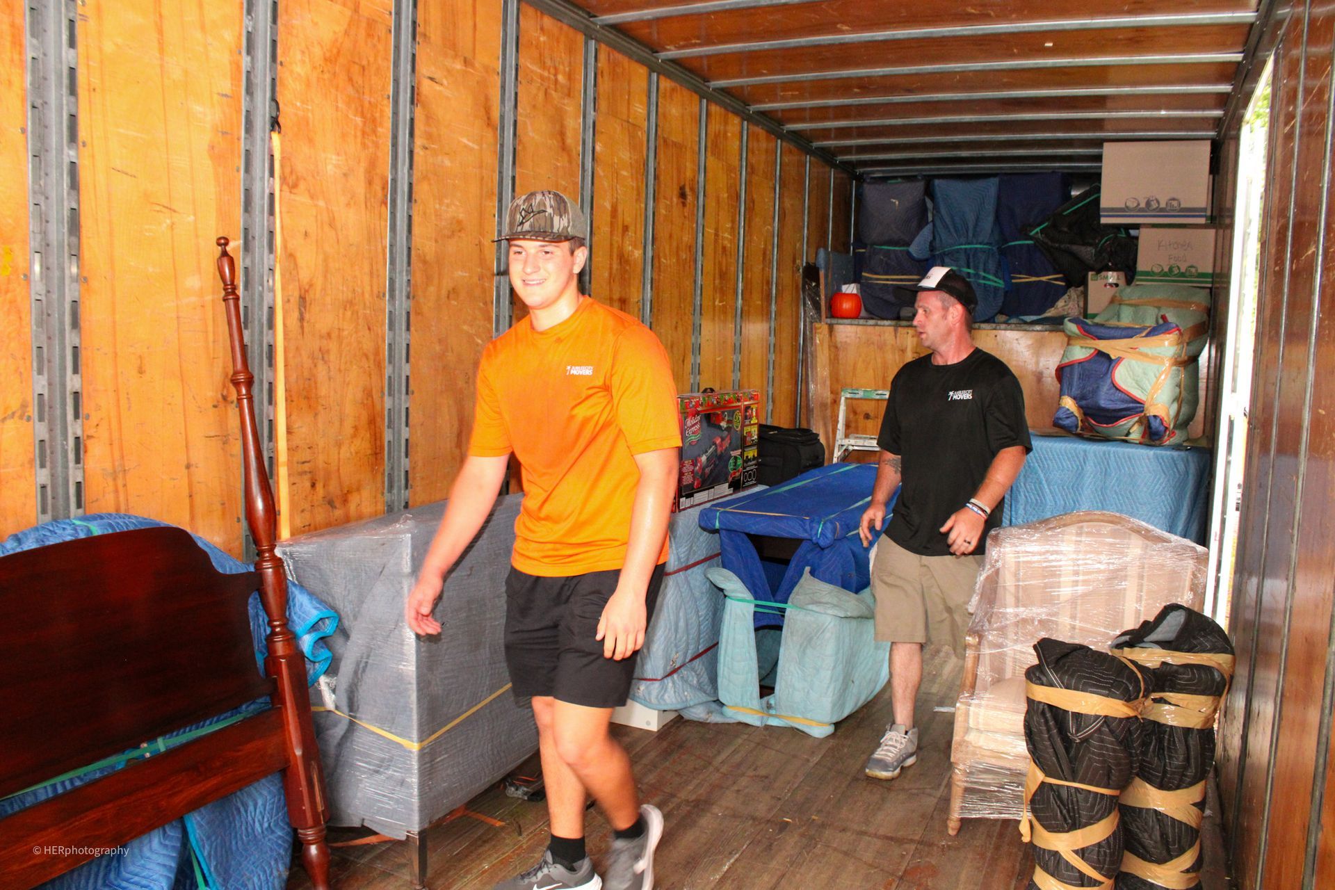 Two men are loading furniture into a moving truck.