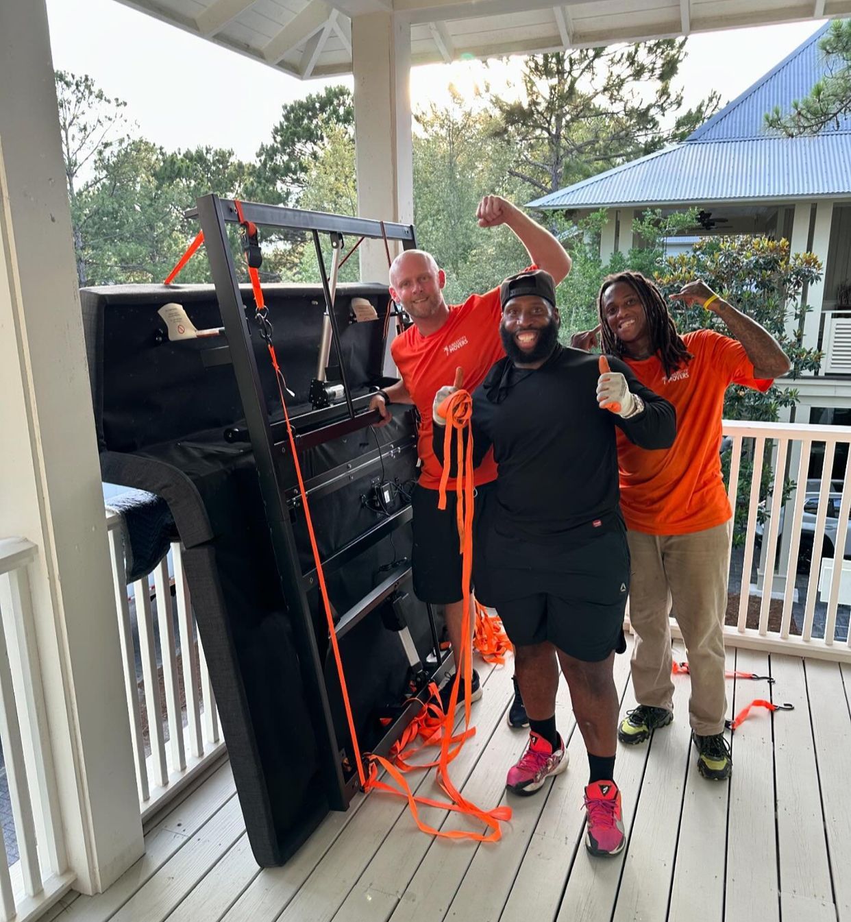 A group of people are standing on a porch holding ropes around a piano