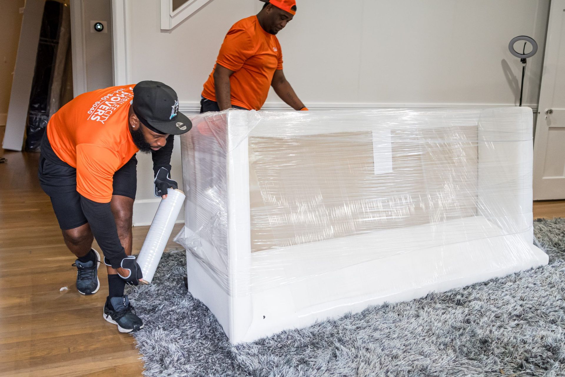 Two men are wrapping a crib in plastic wrap.