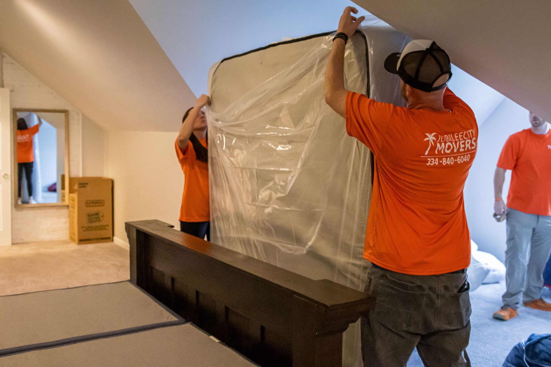 A group of people are moving a mattress in a room.