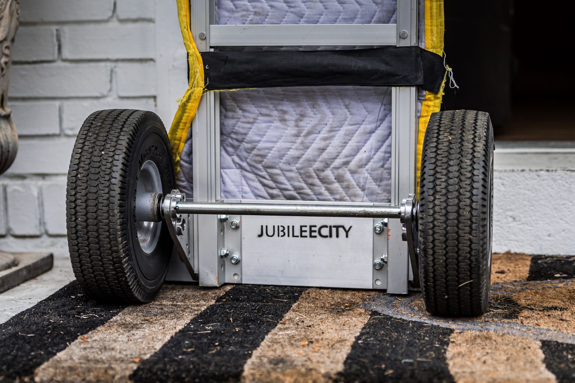 A moving cart is sitting on a striped rug in front of a door.