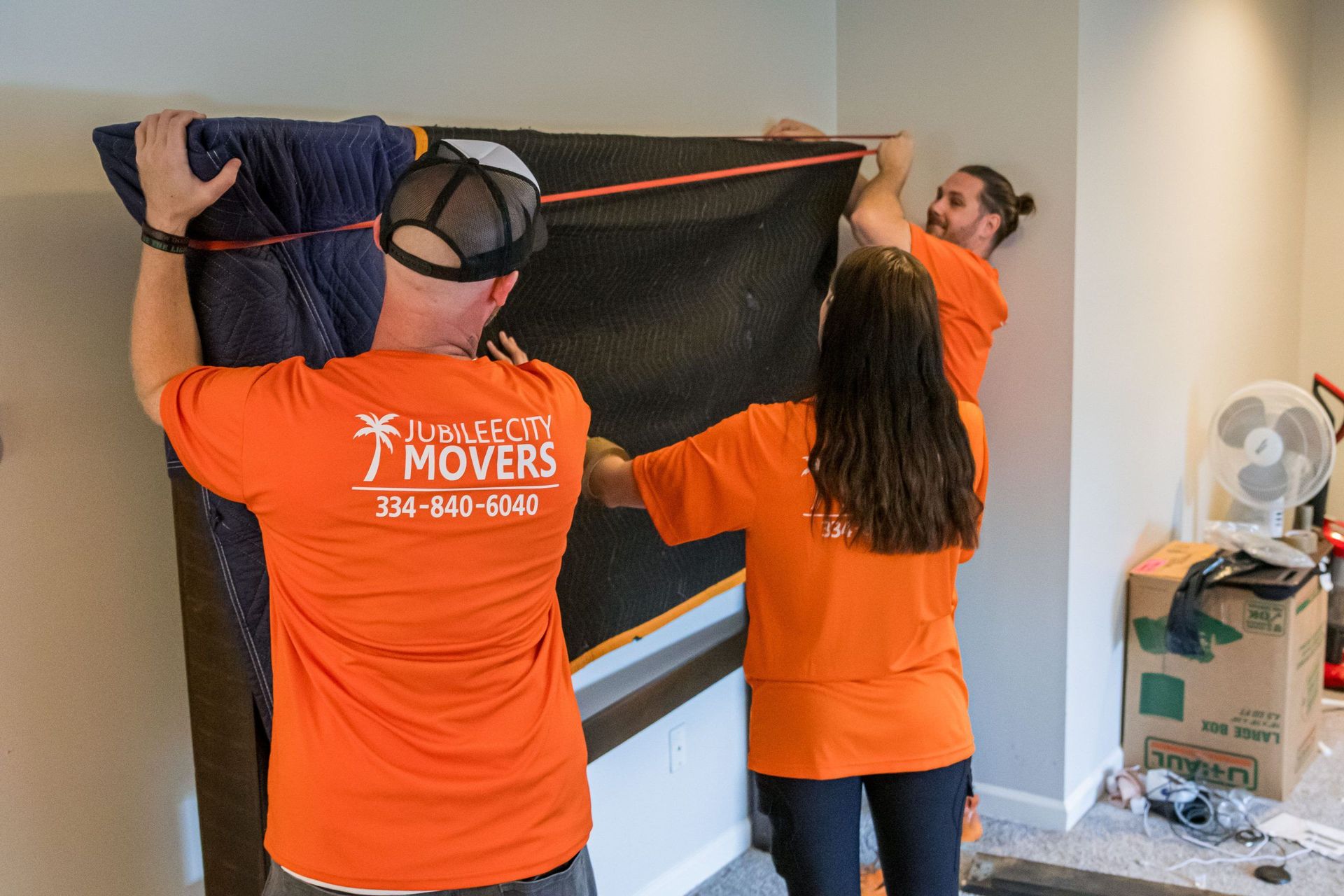 A group of movers are measuring a piece of furniture in a room.
