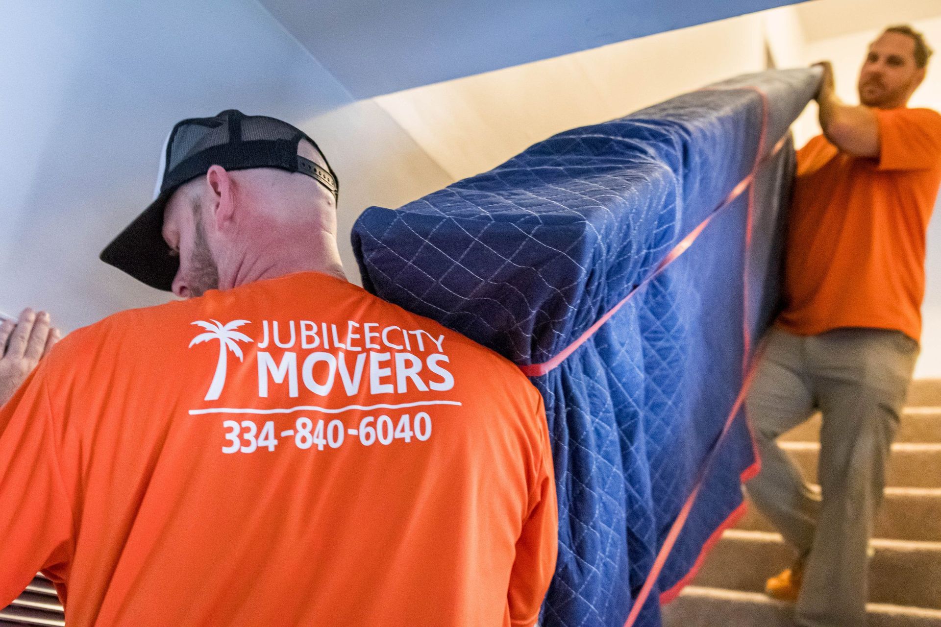 Two men are carrying a large piece of furniture up a set of stairs.