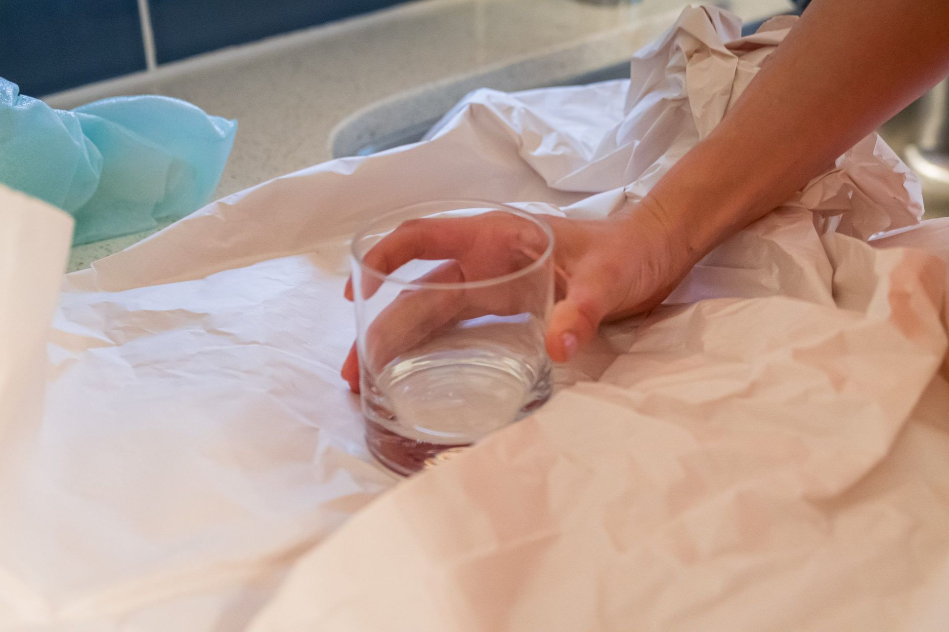 A person is holding a glass of water on a bed.