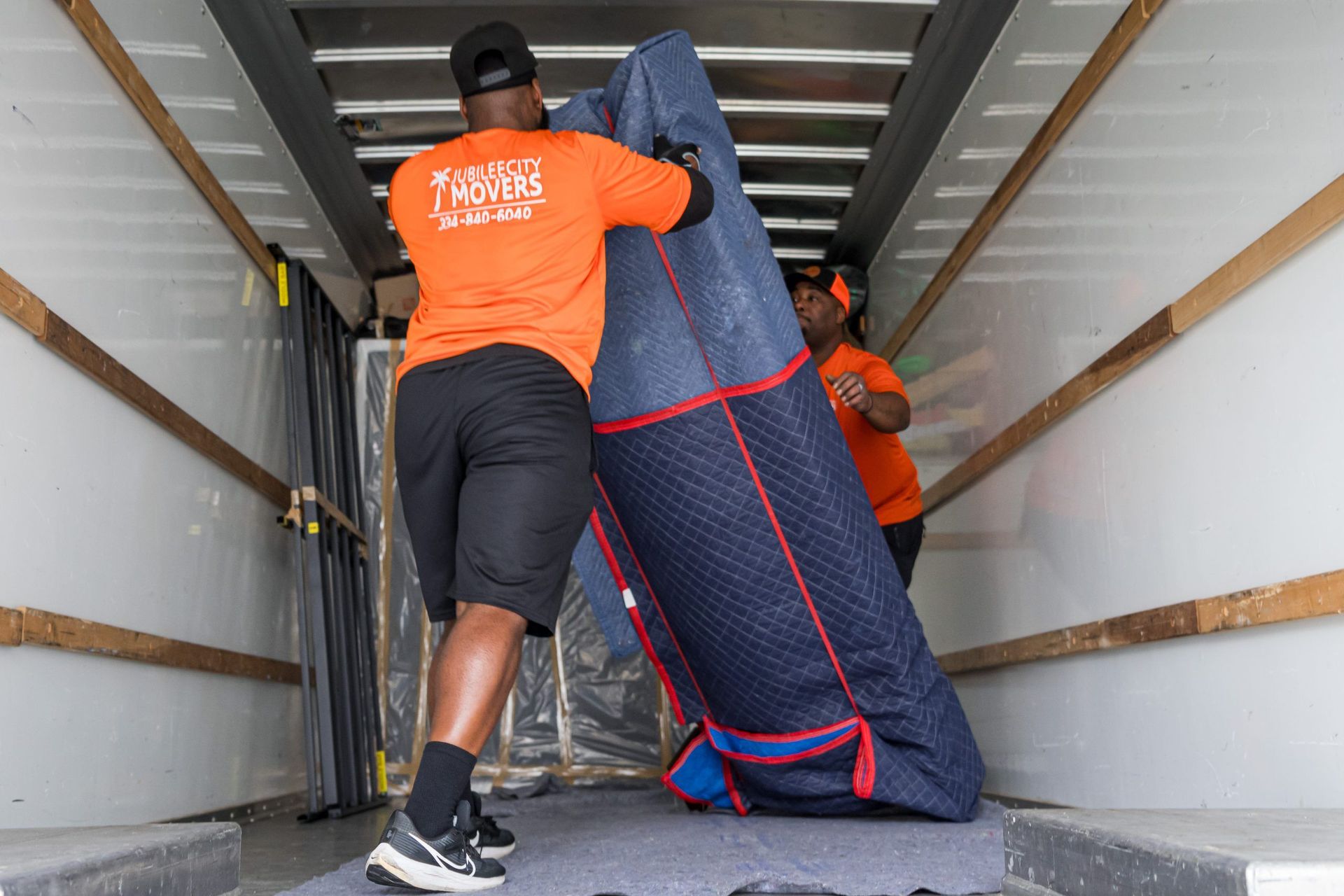 Two men are carrying a large couch in a moving truck.