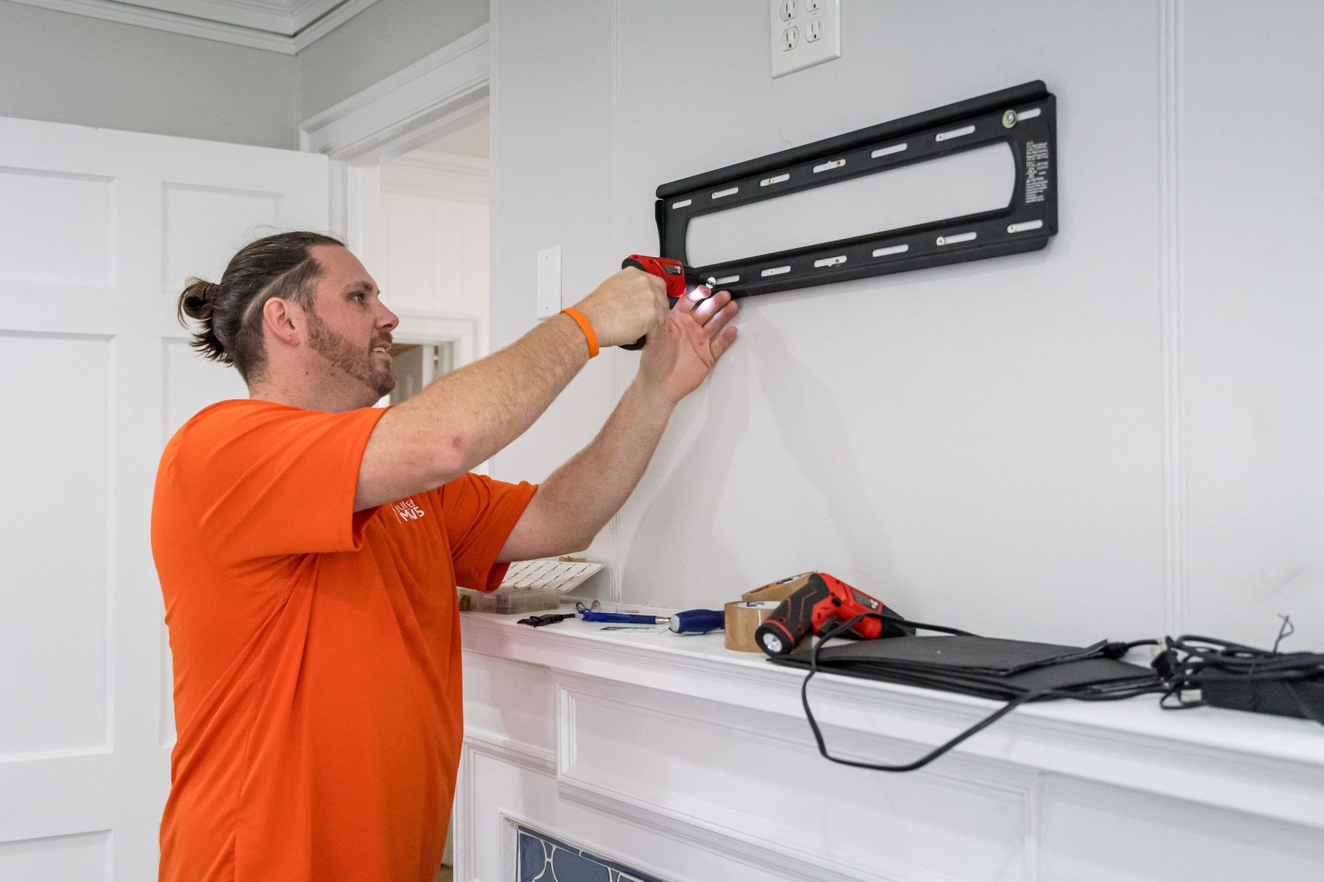 A man is installing a flat screen tv mount on a wall.