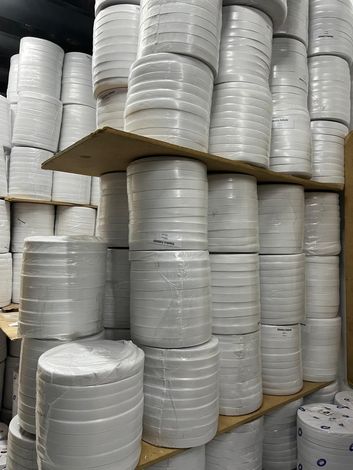 Montones de material blanco enrollado en estantes en un área de almacenamiento de un almacén.