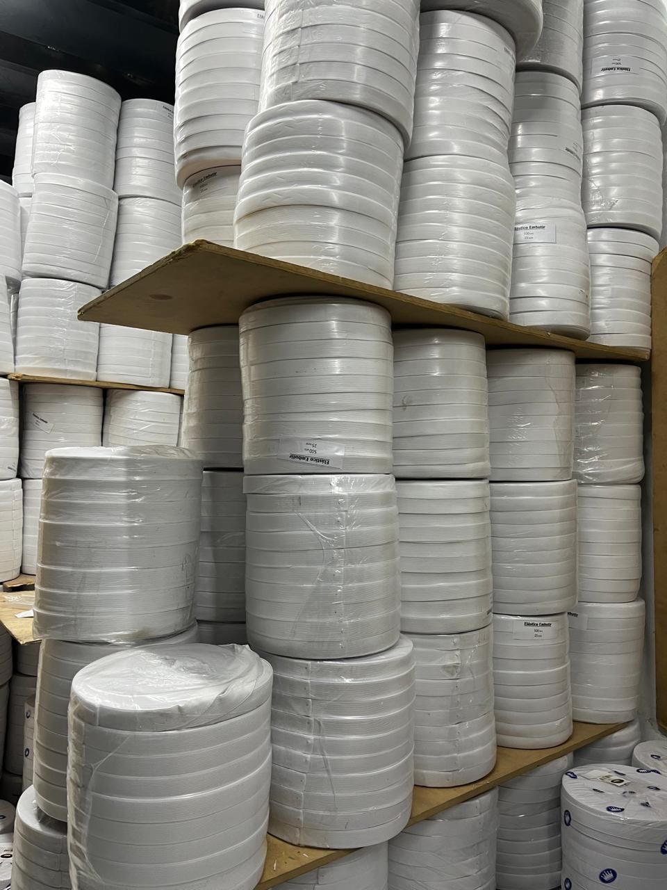 Montones de material blanco enrollado en estantes en un área de almacenamiento de un almacén.